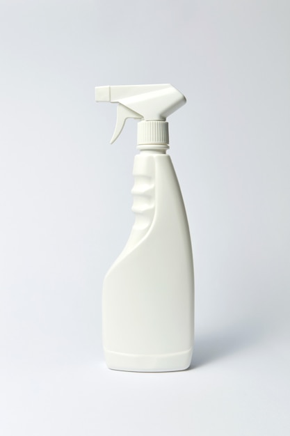 Biała pusta plastikowa butelka detergentu w sprayu na jasnoszarym tle, z miejsca na kopię.