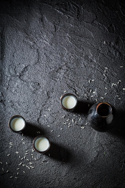 Biała sake w czarnej ceramice na czarnej skale