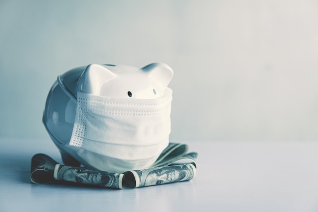 Biała skarbonka bierze maskę z banknotem na stole, aby zaoszczędzić pieniądze