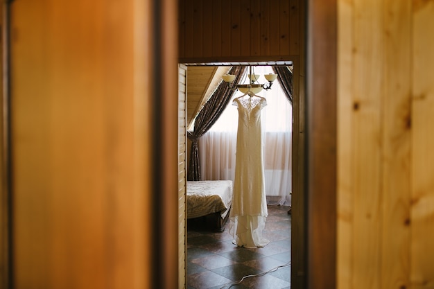 Biała suknia ślubna wisząca na żyrandolu w pokoju