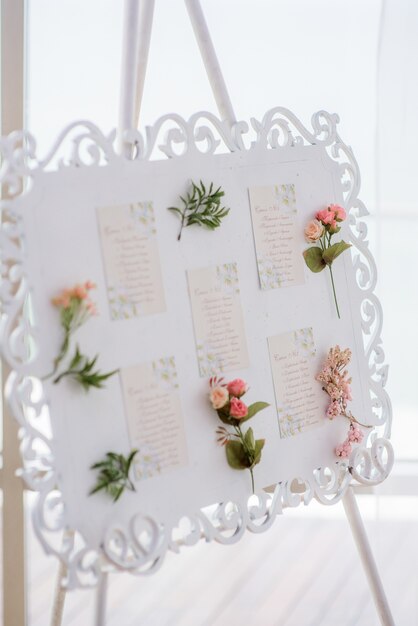 Zdjęcie biała sztaluga z ramą z imionami gości ozdobionymi kwiatami