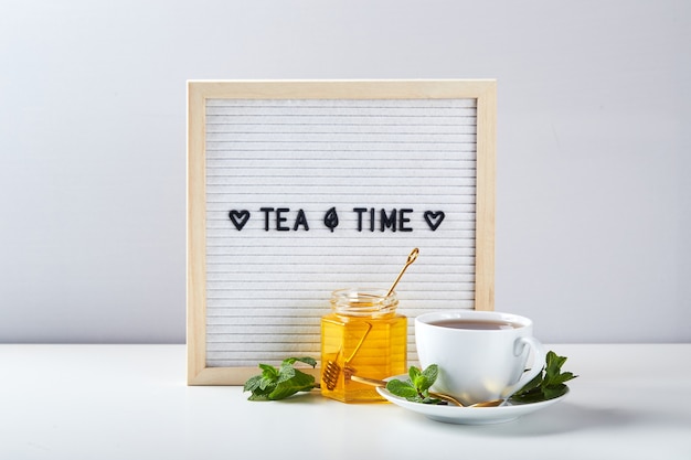 Biała tablica na herbatę z tekstem na marmurowym stole ze szklaną filiżanką herbaty z liśćmi mięty