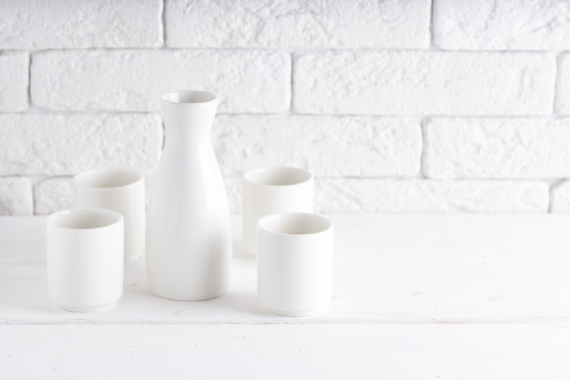 Biała waza i filiżanki na białym stole