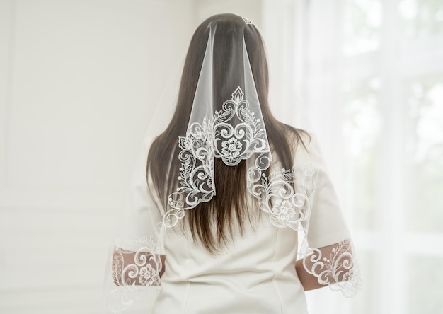 Biała zasłona ślubna pokrywa głowę panny młodej w dzień jej ślubu