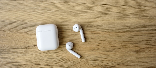 Białe bezprzewodowe słuchawki lub słuchawki na stole do użytku ze smartfonem. Koncepcja technologii