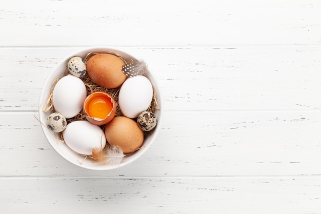 Białe, brązowe i przepiórcze jajka w misce na drewnianym tle Widok z góry z miejsca na kopię Układ płaski