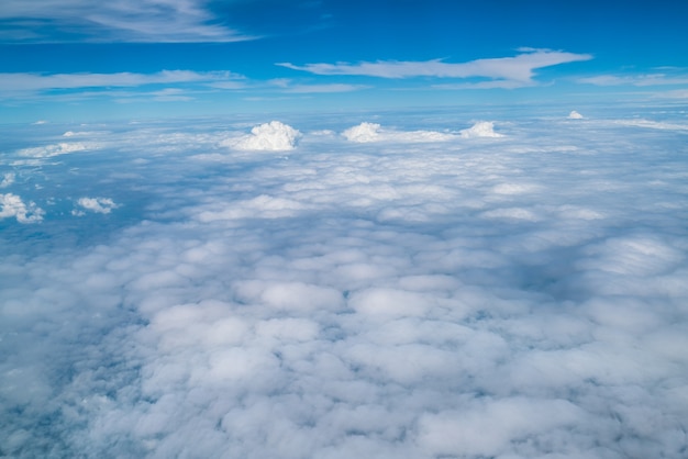 Białe chmury w błękitne niebo widziane z okna samolotu.
