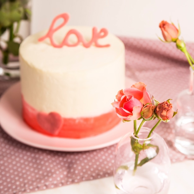 Białe Ciasto Z Różowym Wystrojem I Słowo Miłość Na Górze Wśród Małych Białych I Różowych Róż. Koncepcja Prezent Walentynki