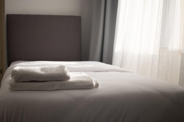 Białe czyste ręczniki ułożone na łóżku hotelowym?