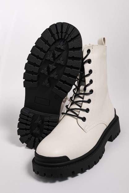 Białe damskie jesienne szorstkie buty wojskowe na traktorowej podeszwie ze sznurowadłami, na białym tle