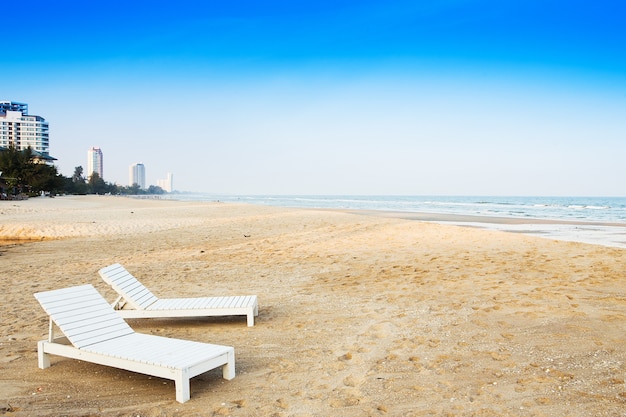 Białe Drewniane Krzesło. Umieszczony Na Piaszczystej Plaży Nad Morzem.