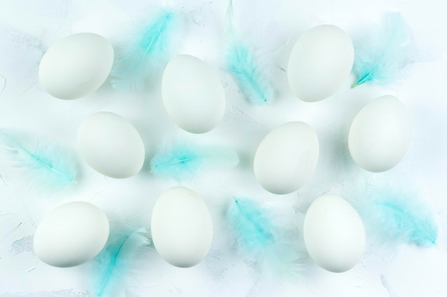 Białe jajka i pióra na białym tle z teksturą Widok z góry