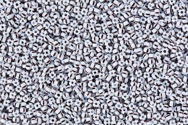 Białe koraliki z czarną linią na teksturze makro