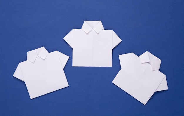 Białe koszule z papieru origami na niebieskim tle