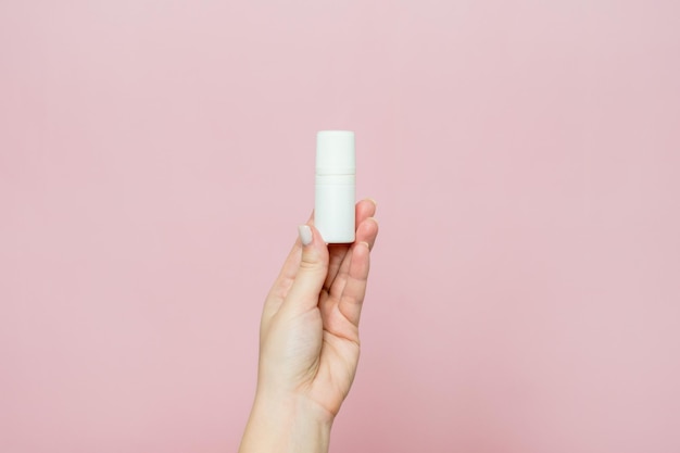 Białe krople do butelek do nosa lub ucha w dłoni na różowym tle Produkt farmaceutyczny