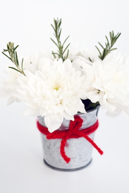 Białe kwiaty i gałązki rozmarynu w małym blaszanym wiaderku