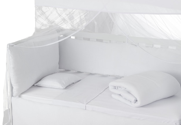 Białe łóżeczko dziecięce z poduszką, kołdrą i muszkieterem na białym tle. Widok Szczegółowy.