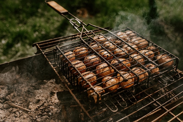 Białe małe okrągłe pieczarki z pieczarkami ułożone w równych rzędach na grillu