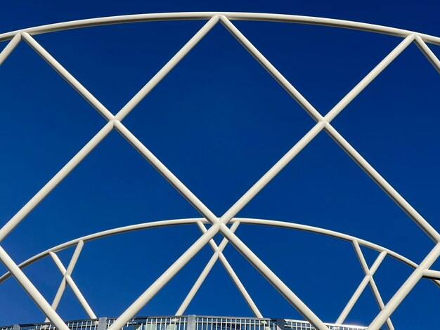 Białe metalowe rury tworzące wzór na tle nowoczesnej architektury błękitnego nieba