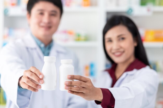Białe Plastikowe Butelki Leku Na Trzymanie Ręki Mężczyzny I Kobiety Farmaceuta Azjatyckiego W Aptece Tajlandii Z Bliska I Selektywnej Ostrości
