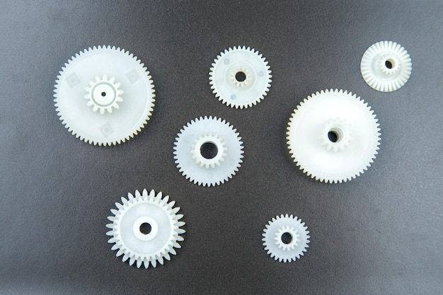 Białe plastikowe koła zębate na ciemnym tle mechanizm łączący szczegółowo opisuje przedmiot ruchu