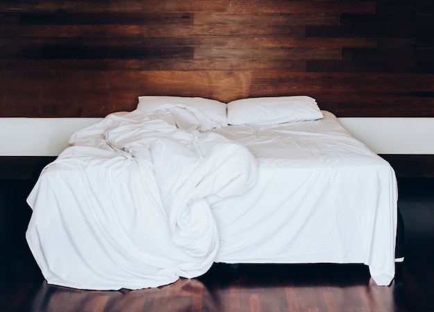 Zdjęcie białe poduszki na prześcieradle i koc z pomarszczonym bałaganem w sypialni