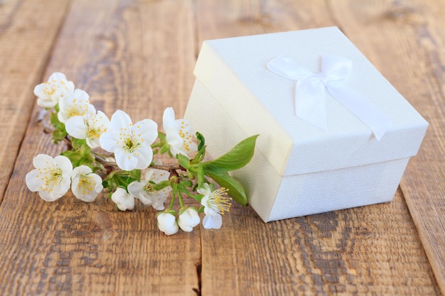 Białe pudełko ozdobione kwiatami jaśminu na starych drewnianych deskach.