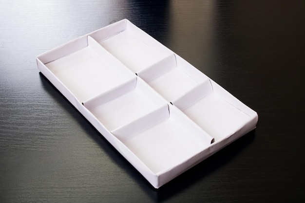 Białe pudełko z komórkami na drewnianym stole