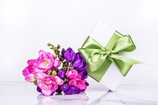 Białe Pudełko Z Zieloną Jedwabną Kokardą I Różowym I Fioletowym Bukietem Kwiatów Na Białym Tle
