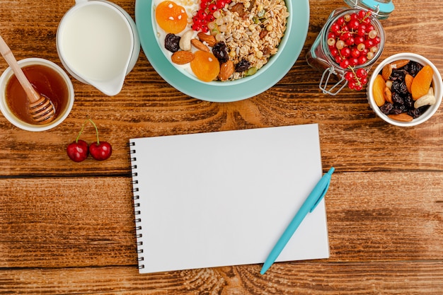 Zdjęcie białe puste miejsce dziennika żywności, zdrowe śniadanie z muesli z owocami, mlekiem i miodem na drewnianym stole.