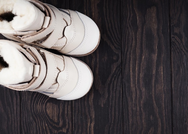 Białe skórzane buty dziecięce na drewnianym tle, kopia przestrzeni.