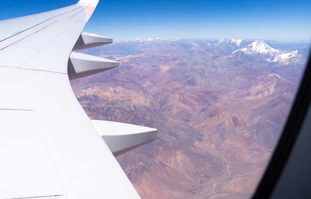 Białe skrzydło z okna samolotu, a poniżej pasmo górskie Andów w słoneczny dzień