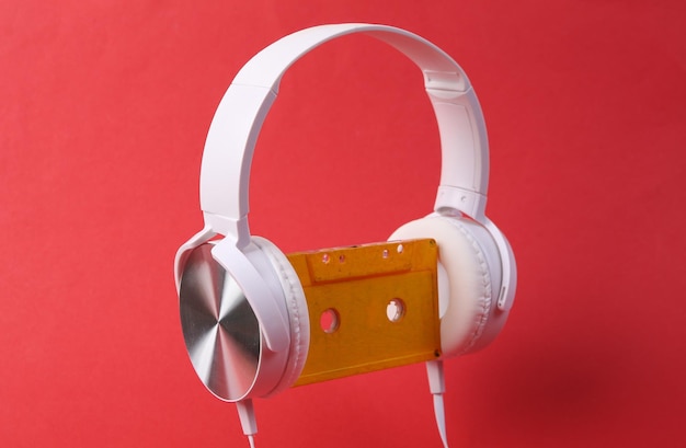 Białe słuchawki stereo z retro kasetą audio na czerwonym tle koncepcja muzyki z lat 80.