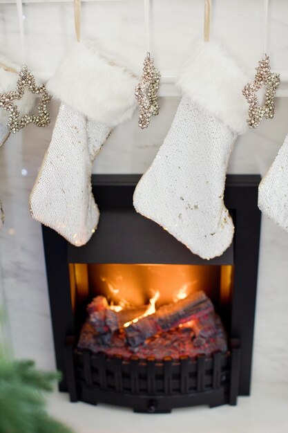 Zdjęcie białe świąteczne skarpetki i srebrne gwiazdki z dzwoneczkami wiszą na kominku świąteczne prezenty w skarpetkach