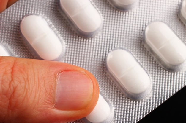 Białe tabletki w blistrze w dłoni z bliska