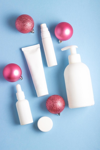 Białe tuby z kosmetykami na niebieskim tle z dekoracjami świątecznymi Zimowe produkty do pielęgnacji skóry Baner świąteczny z miejsca kopiowania tekstu