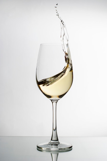 Zdjęcie białe wino pluskające z eleganckiego kieliszka