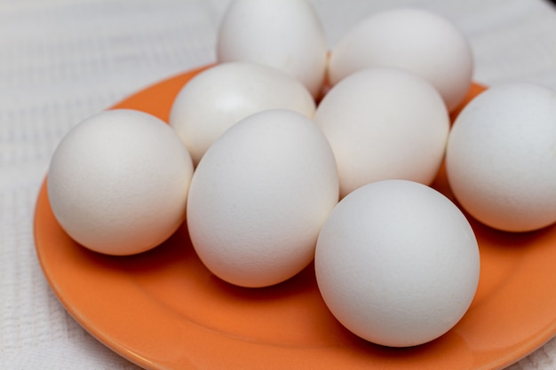 Biali jajka na pomarańczowym talerza zakończeniu up