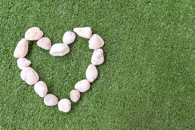 Zdjęcie biali kamienie kierowy kształt na trawy zieleni tle dla miłości