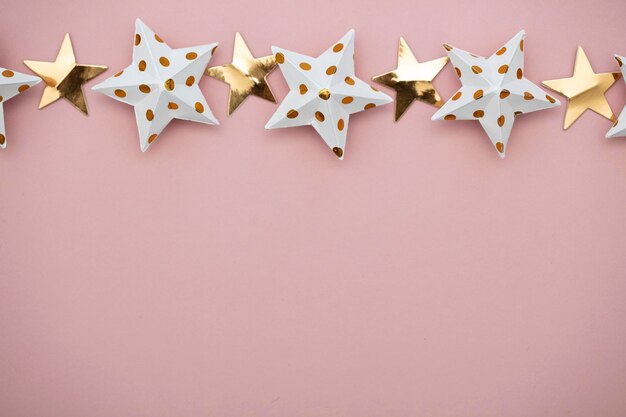Biało-złote dekoracje gwiazd na pastelowym różowym tle Świątecznym sezonowym
