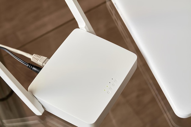 Zdjęcie biały bezprzewodowy router wi-fi w pobliżu laptopa na szklanym stole
