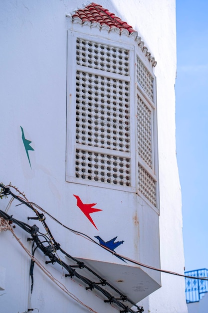 Biały budynek z czerwono-niebieskim wzorem ptaka z boku.