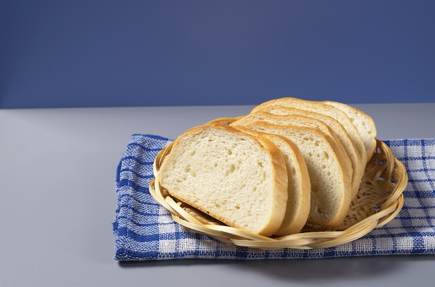 Biały chleb w wiklinowym drewnianym talerzu na kuchennym stole