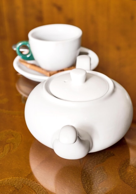 Biały czajniczek i pusta filiżanka herbaty na stole