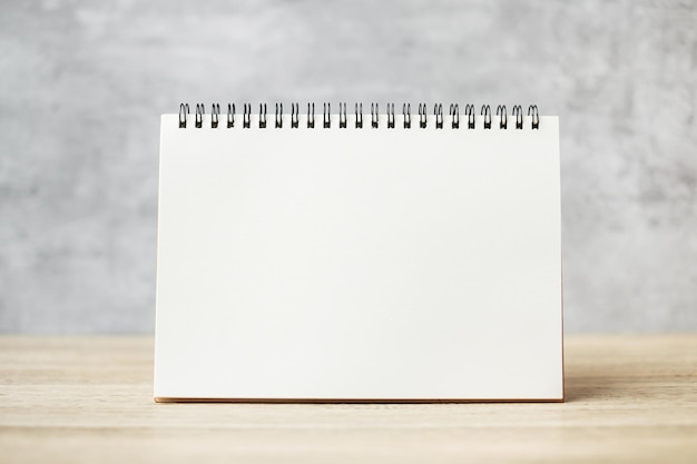 Biały czysty papierowy notatnik lub kalendarz na drewnianym stole z miejscem na tekst, szablon i makiety koncepcji