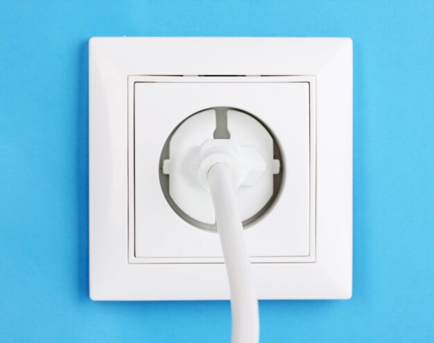 Zdjęcie biały gniazdo elektryczne z wtyczką na ścianie