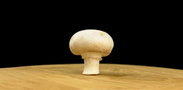 Biały grzyb na drewnianej desce na czarnym tle, koncepcja organicznych i naturalnych składników zdjęcie