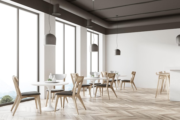 Biały kąt restauracji z drewnianą podłogą, okrągłe białe stoły i szare i drewniane krzesła.