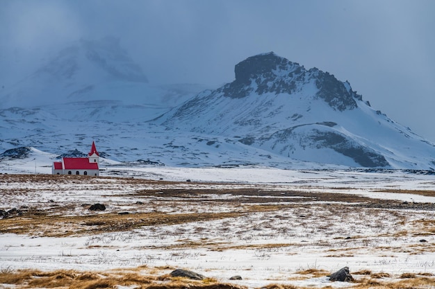 Biały kościół z czerwonym dachem w śnieżnym krajobrazie Hellisandur Islandia