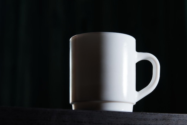 Biały kubek na herbatę i kawę na ciemnym tle zbliżenia